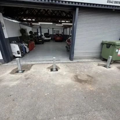 Three telescopic security posts installed across a workshop entrance