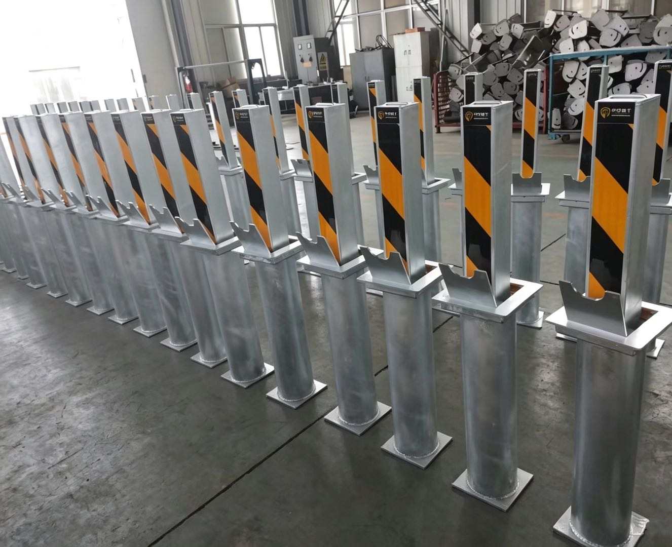 Original supplier factory photograph of multiple hot-dip galvanised rising security posts with reflective black-and-yellow face markings